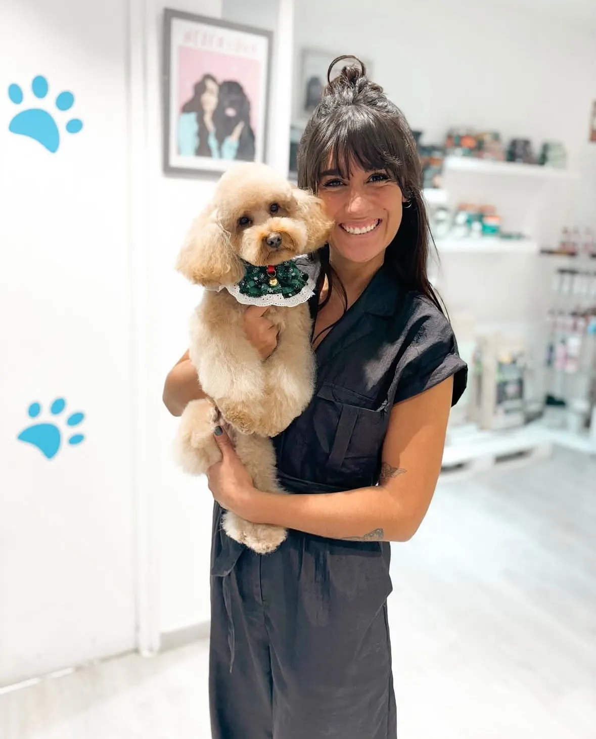 Nerea sonriendo con un caniche color crema con collar de Navidad