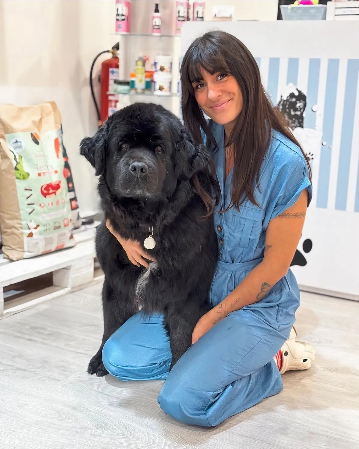 Nerea Galarza abrazando a Ova, su perra Terranova negra, en la tienda de Dogneer